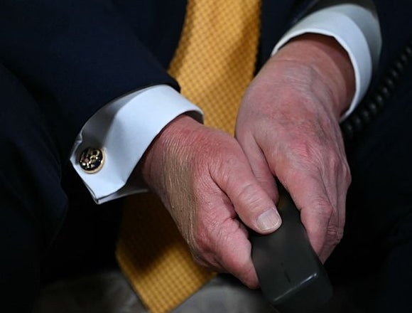 Person i forretningsdrakt med gult slips, som holder en fjernkontroll for TV. Hender og mansjetter er synlige