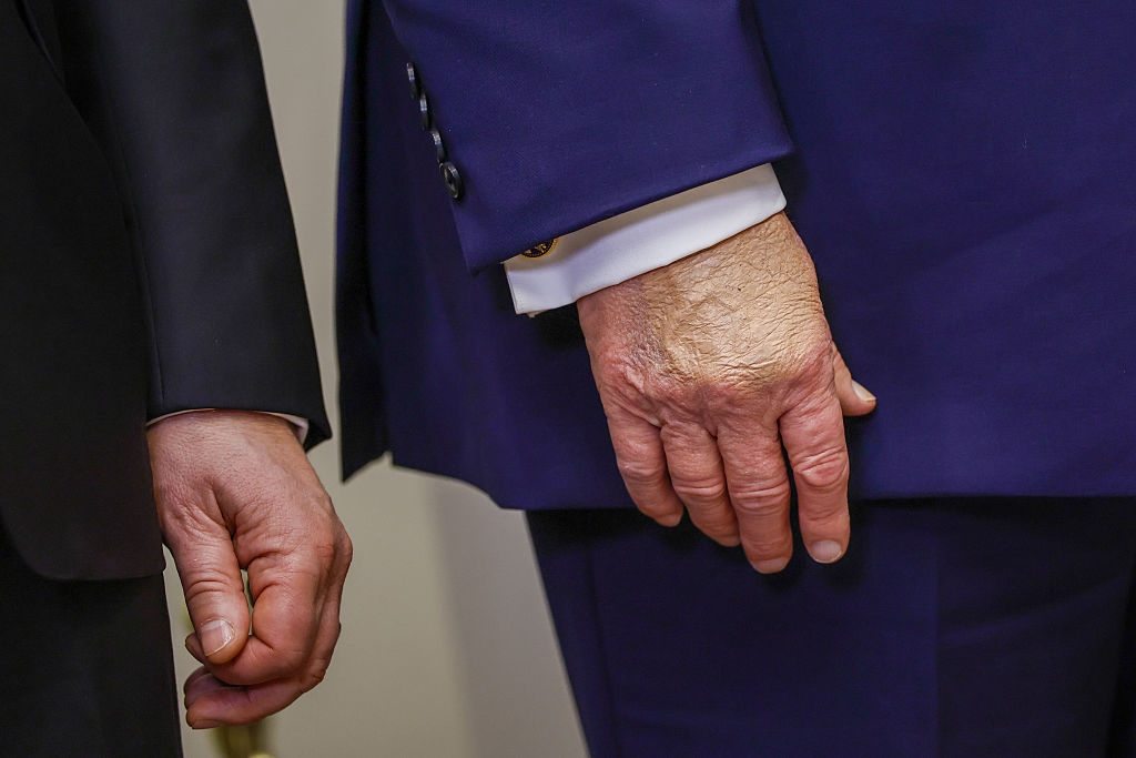 To individer i formelle dresser som står side om side; fokuset er på hendene og klesdetaljene i stedet for ansiktene