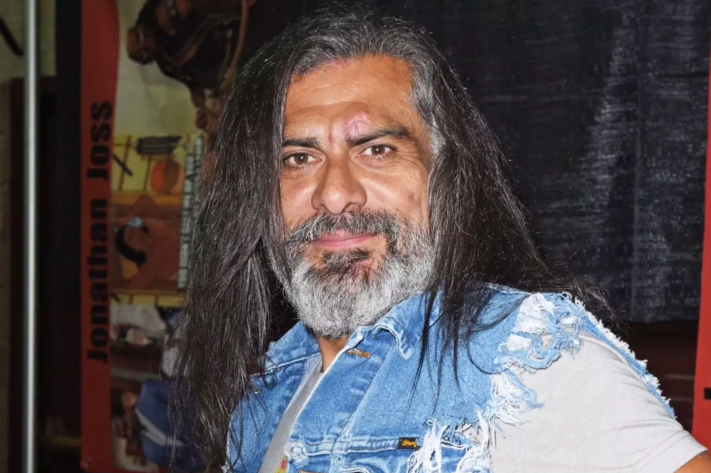 Person med langt hår og skjegg iført dongerivest på et offentlig arrangement