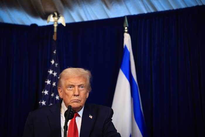 A idiosyncratic   stands astatine  a podium with a microphone, U.S. and Israeli flags down  them successful  a property   league  setting