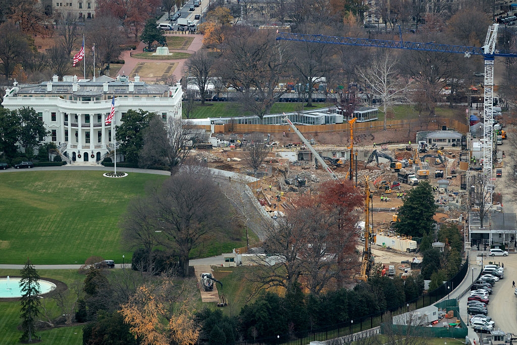 Aerial presumption of the White House with adjacent operation site, cranes, and equipment, surrounded by trees and roads