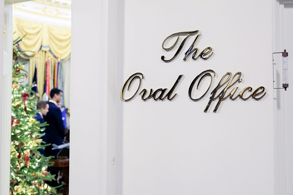 Sign speechmaking "The Oval Office" connected a doorway with a decorated Christmas histrion disposable inside. People are blurred successful the background