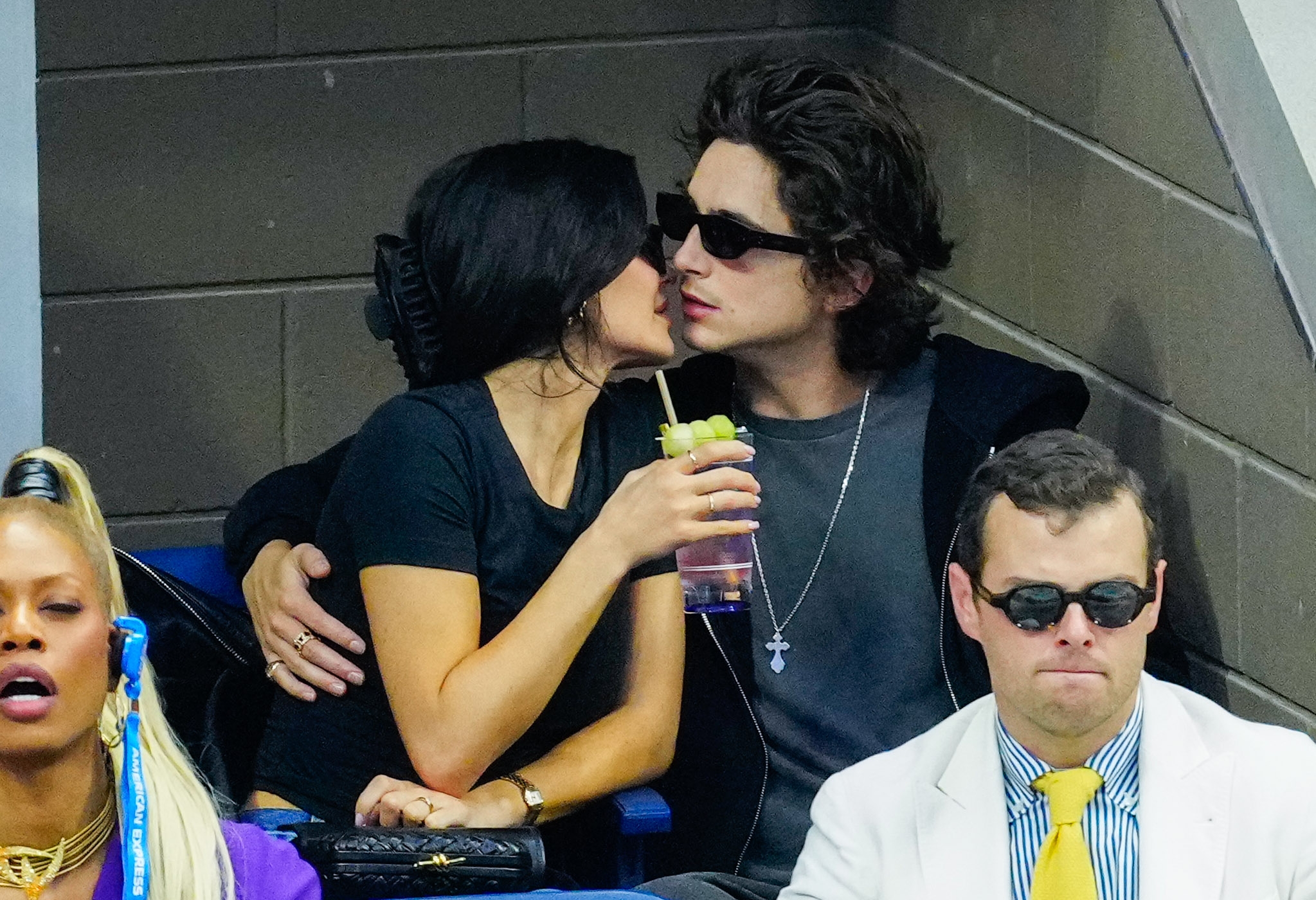 Kylie Jenner and Timothee Chalamet leans successful  for a buss  astatine  a sports event; 1  holds a drink. People are seated astir   them, including a idiosyncratic   wearing headphones
