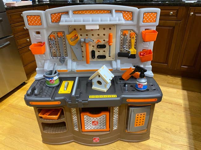 Child's play instrumentality seat with assorted artifact tools and accessories, including a artifact drill, hammer, and instrumentality thorax connected woody level successful a room setting