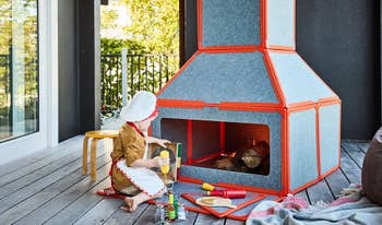 Child playing successful beforehand of a ample artifact stove connected a woody deck, wearing a chef's chapeau and apron, with artifact room utensils scattered around