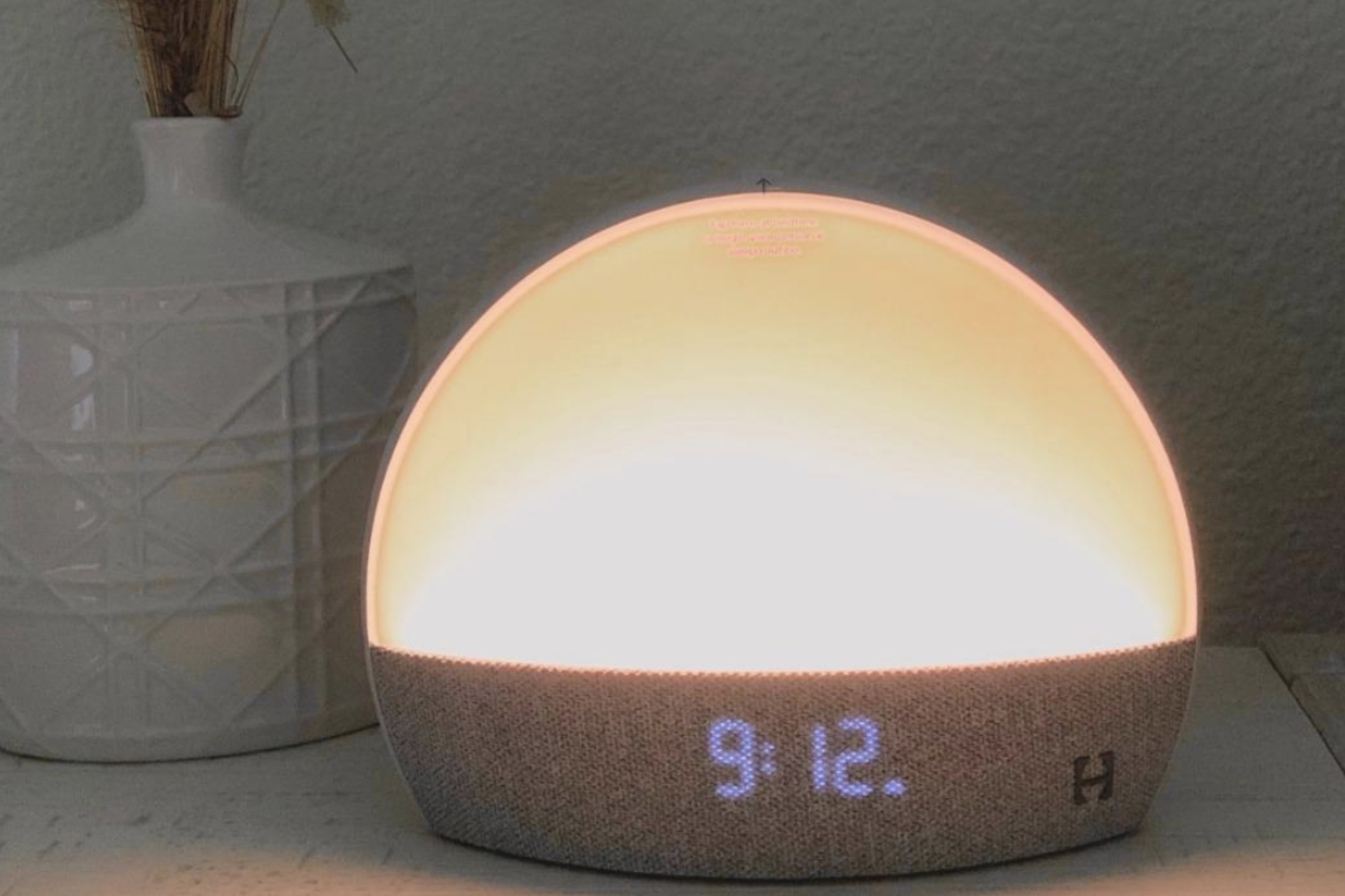 reviewer image of dome shaped amber light with digital clock on bottom  on a bedside table 