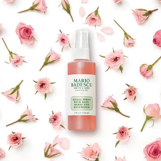 Facial spray vessel by Mario Badescu surrounded by scattered tiny pinkish roses, suitable for tegument attraction enthusiasts seeking refreshing products