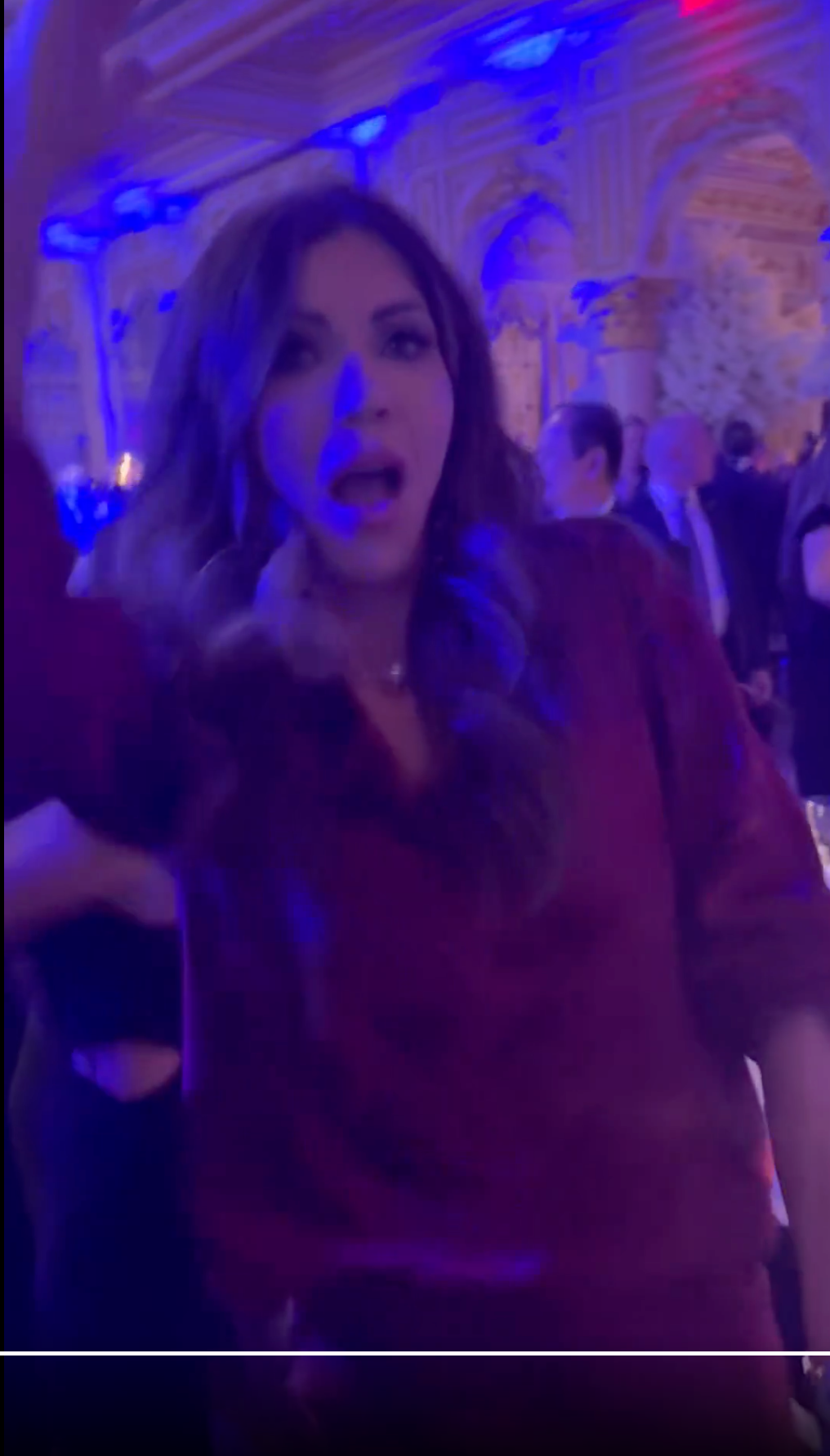 Person i en livlig festsetting, iført en skjorte med avslappet passform, med uttrykk for overraskelse eller spenning