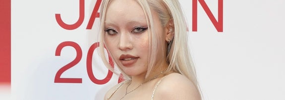 レースのドレスを着た女性がレッドカーペットでポーズを取っている。背景に「AWARDS JAPAN 2021」の文字。