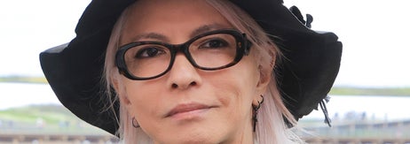 わかりません。女性がフォーマルな黒いスーツと帽子を着用しています。