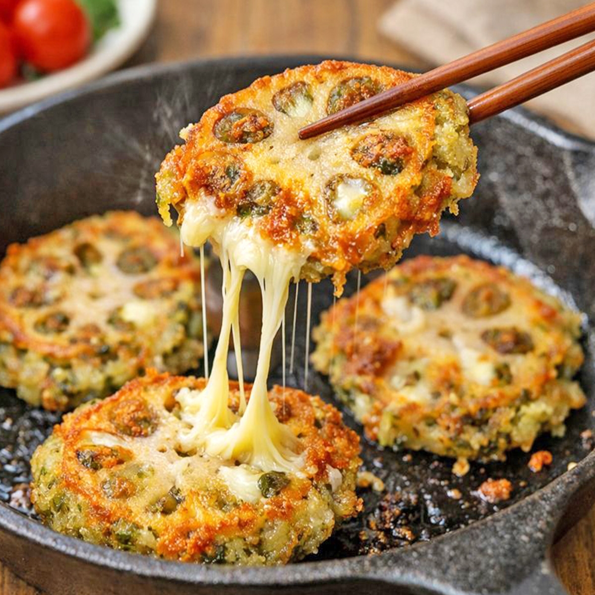 蓮根チーズのフライ、箸で持ち上げられ、他のフライがフライパンに並ぶ。
