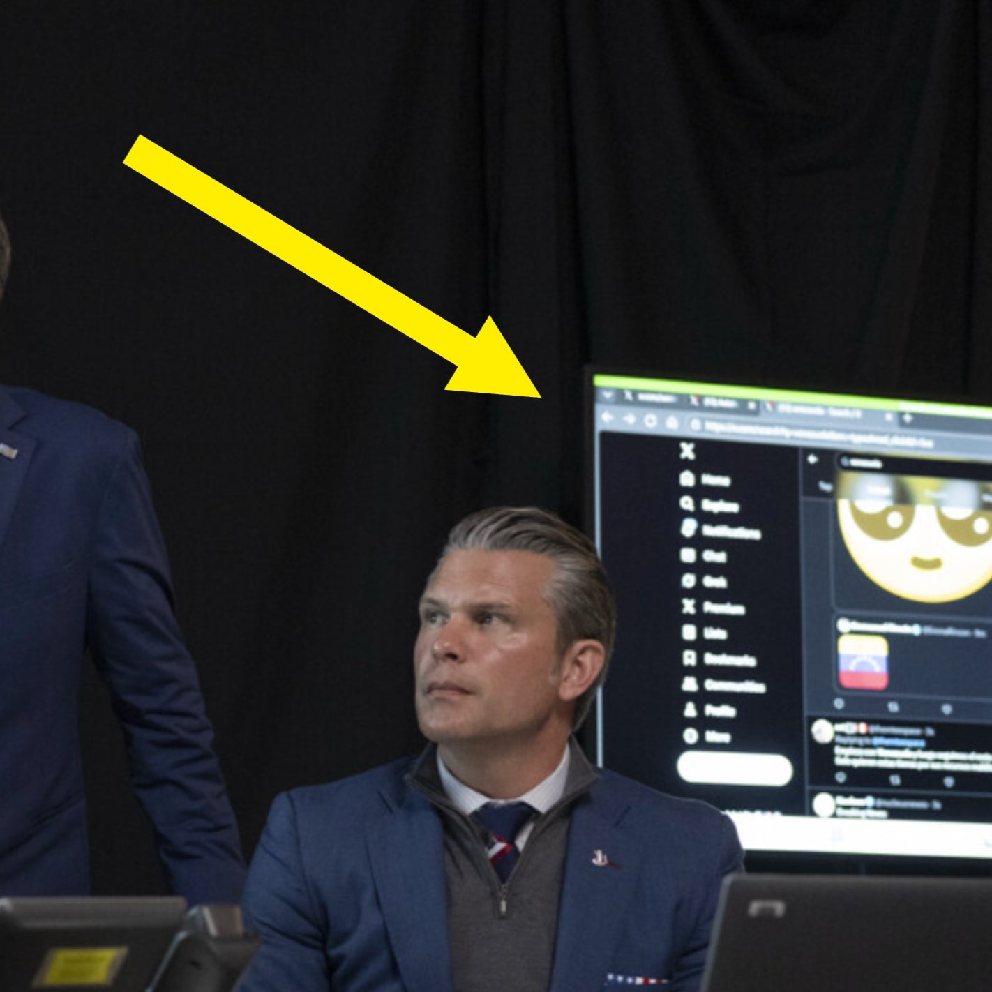 Tre personer i dress sitter og står ved et bord med bærbare datamaskiner og kommunikasjonsenheter, og virker fokuserte og engasjerte i en oppgave