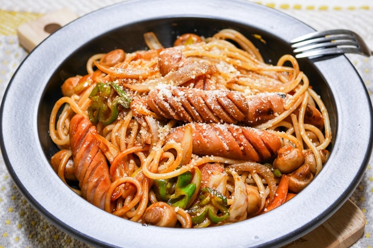 皿に盛られたスパゲッティナポリタンとソーセージ、野菜がトッピングされています。