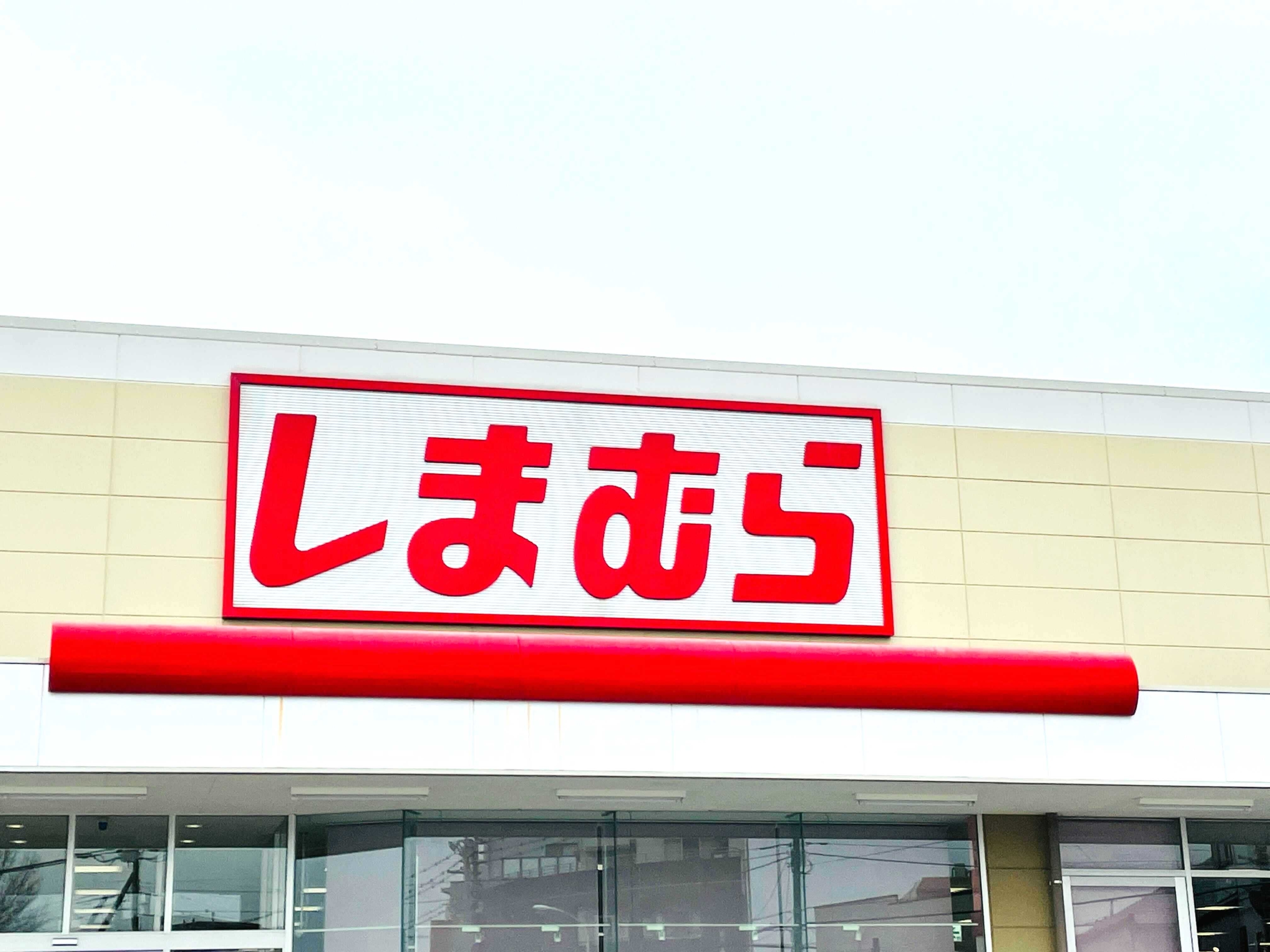 Storefront of a Shimamura retail location with a red sign featuring Japanese characters and glass entrance doors