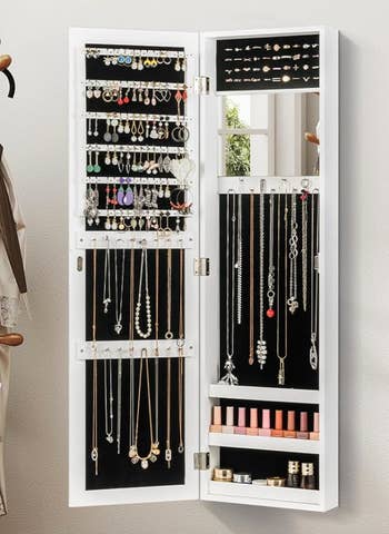 An unfastened jewelry furniture displays assorted earrings, necklaces, rings, and rows of lipstick, neatly organized