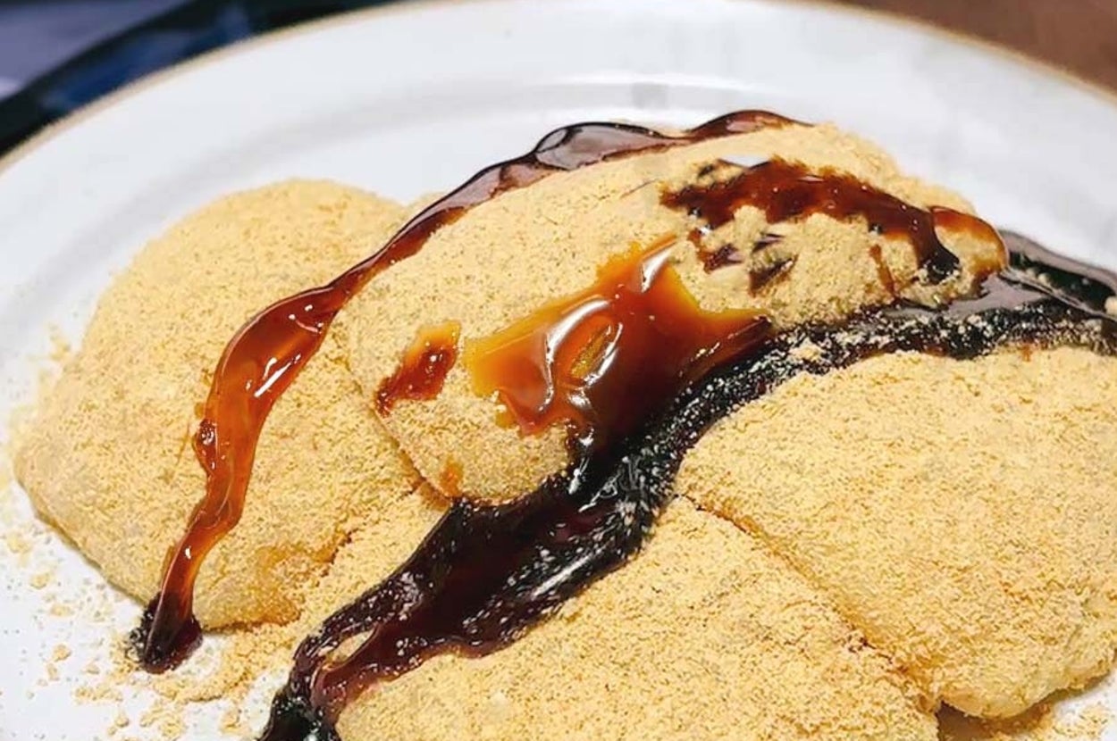 わらび餅が白い皿に盛られ、きな粉と黒蜜がかかっています。滑らかな食感が特徴の和菓子です。