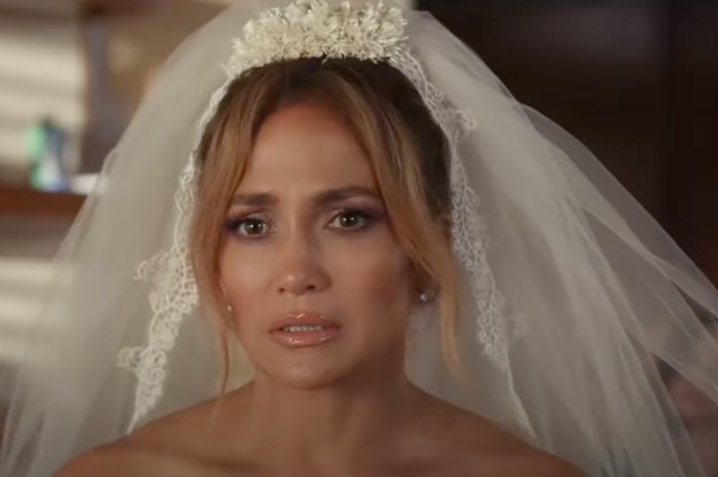 Person in a bridal veil with a floral headpiece looks emotionally distressed indoors