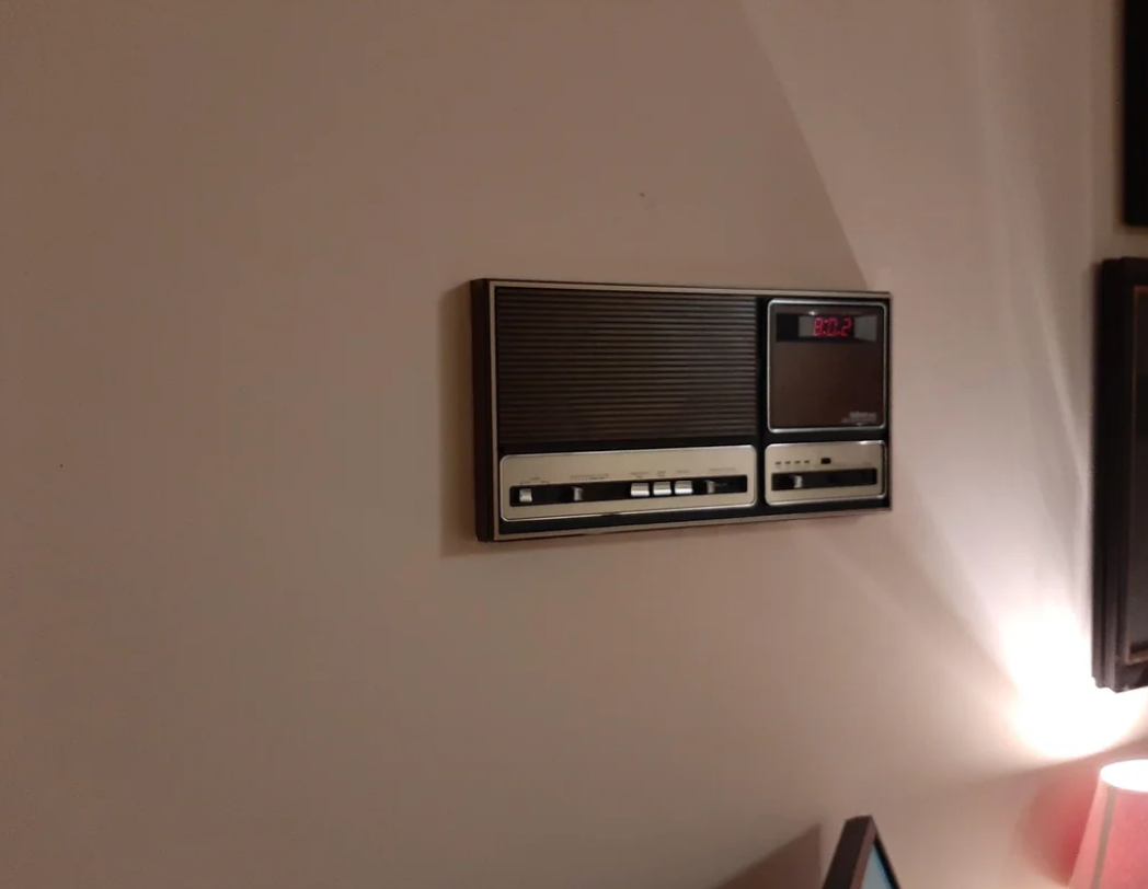 A vintage wall-mounted radio and cassette player with a digital clock display showing the time as 2:32