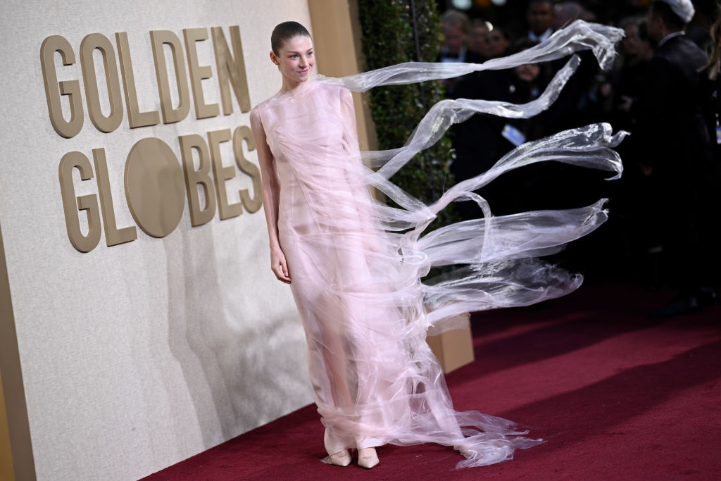 Person in a sheer, flowing gown poses on the red carpet at the Golden Globes event