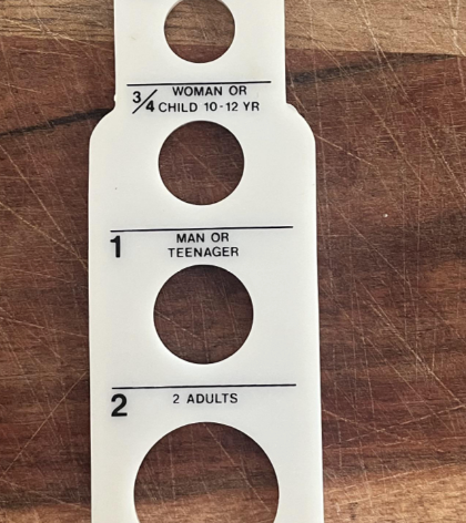 Spaghetti portion measurer on a wooden surface, labeled for child, adult, and family servings by weight and age guide