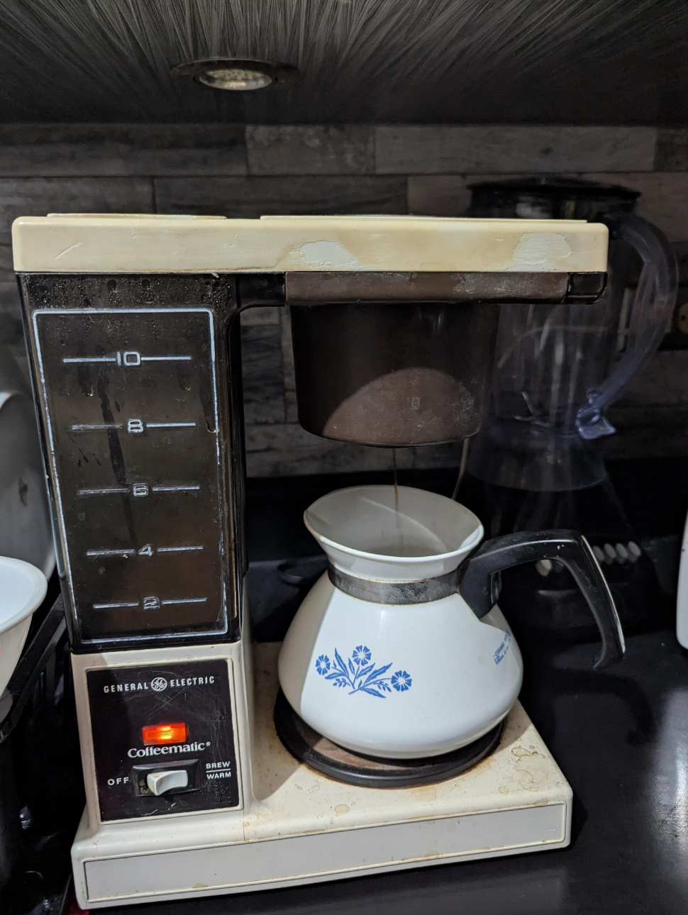 Coffee maker brewing into a floral-patterned carafe on a kitchen counter