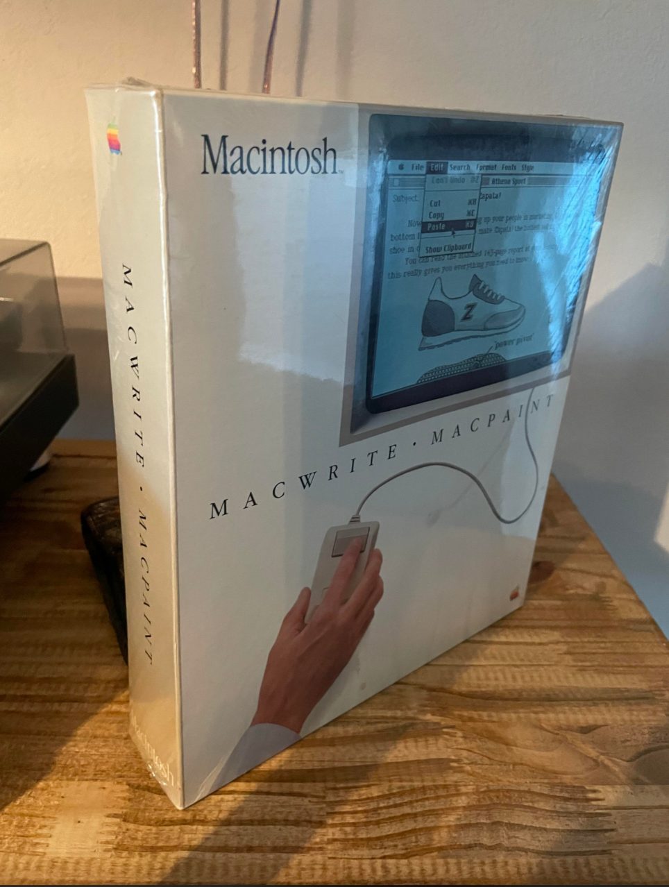 Box of vintage Macintosh software, MacWrite and MacPaint, showcasing a hand using a mouse and a screen with graphic and text editing features