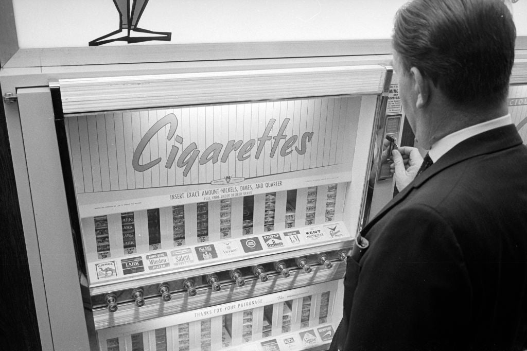 Person astatine  a cigaret  vending machine, selecting a pack. Display shows antithetic  brands