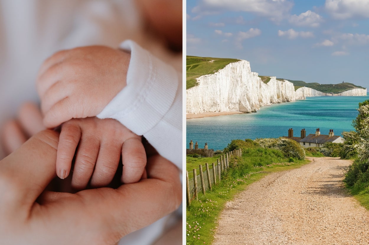 Close-up of a baby’s hand held by an adult's hand; coastal path leading to white cliffs and sea under a blue sky