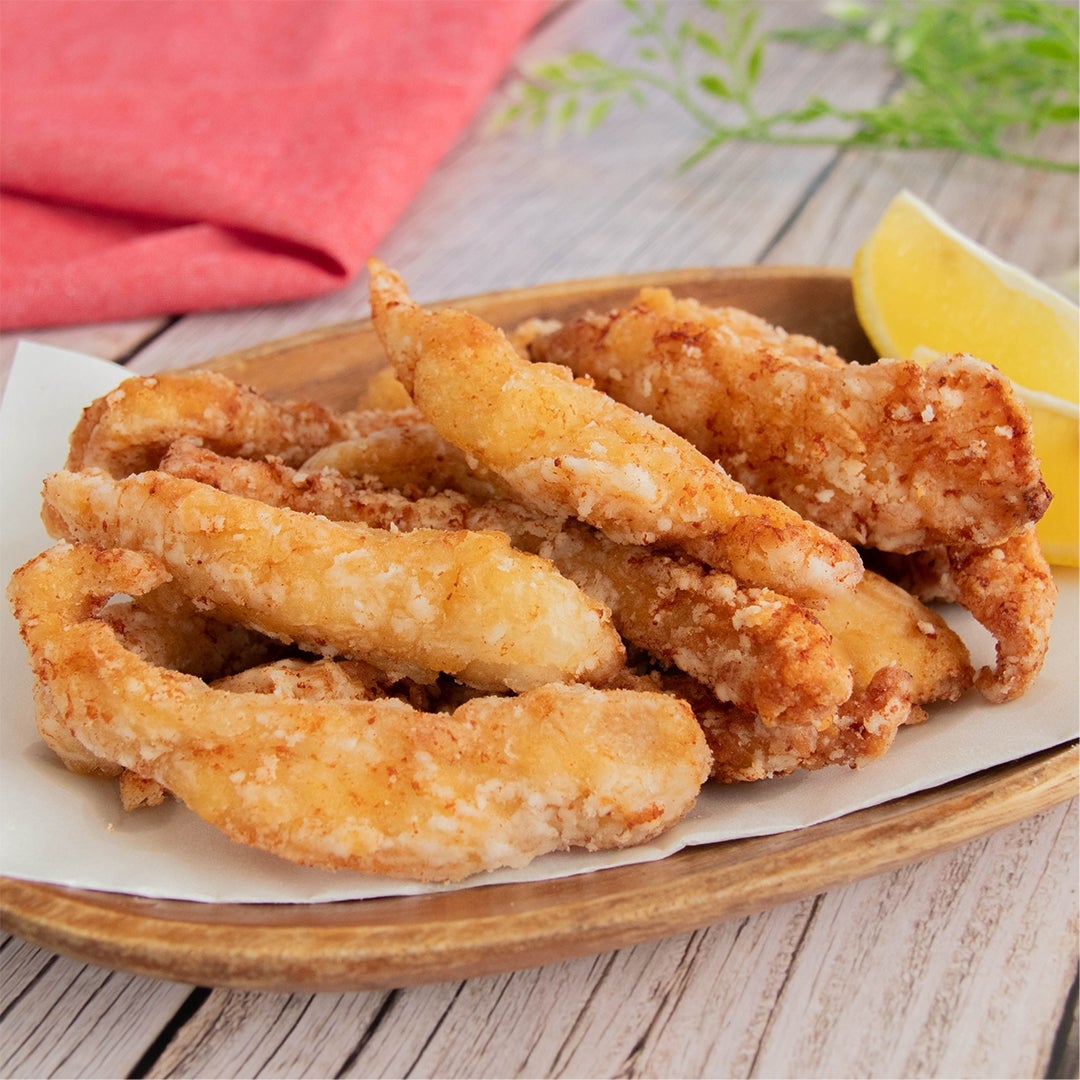 レモンと一緒に盛り付けられた揚げた鶏むね肉のスティック唐揚げ。