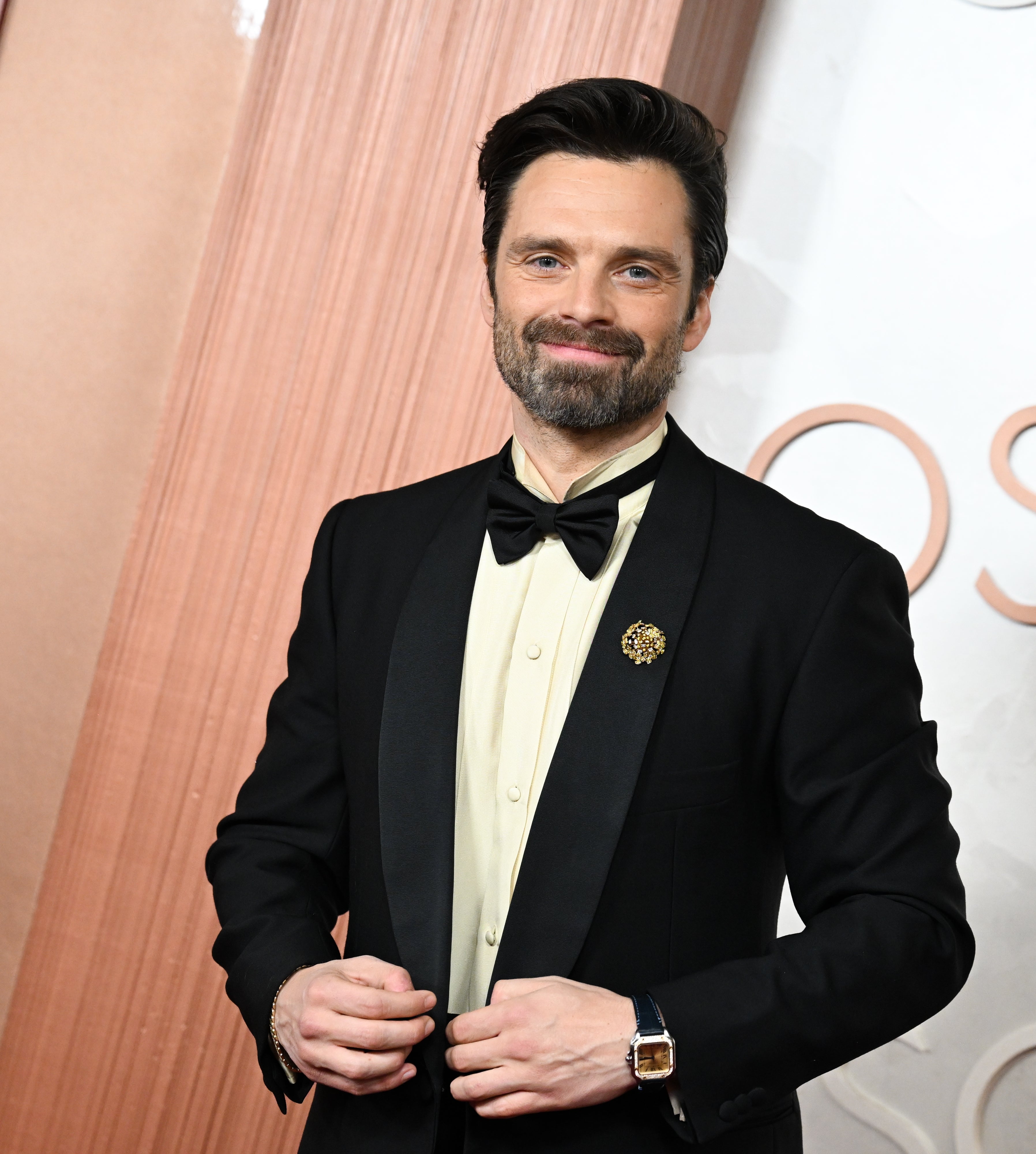 Person successful  a tuxedo with bow necktie  connected  the reddish  carpet astatine  a ceremonial  event, smiling