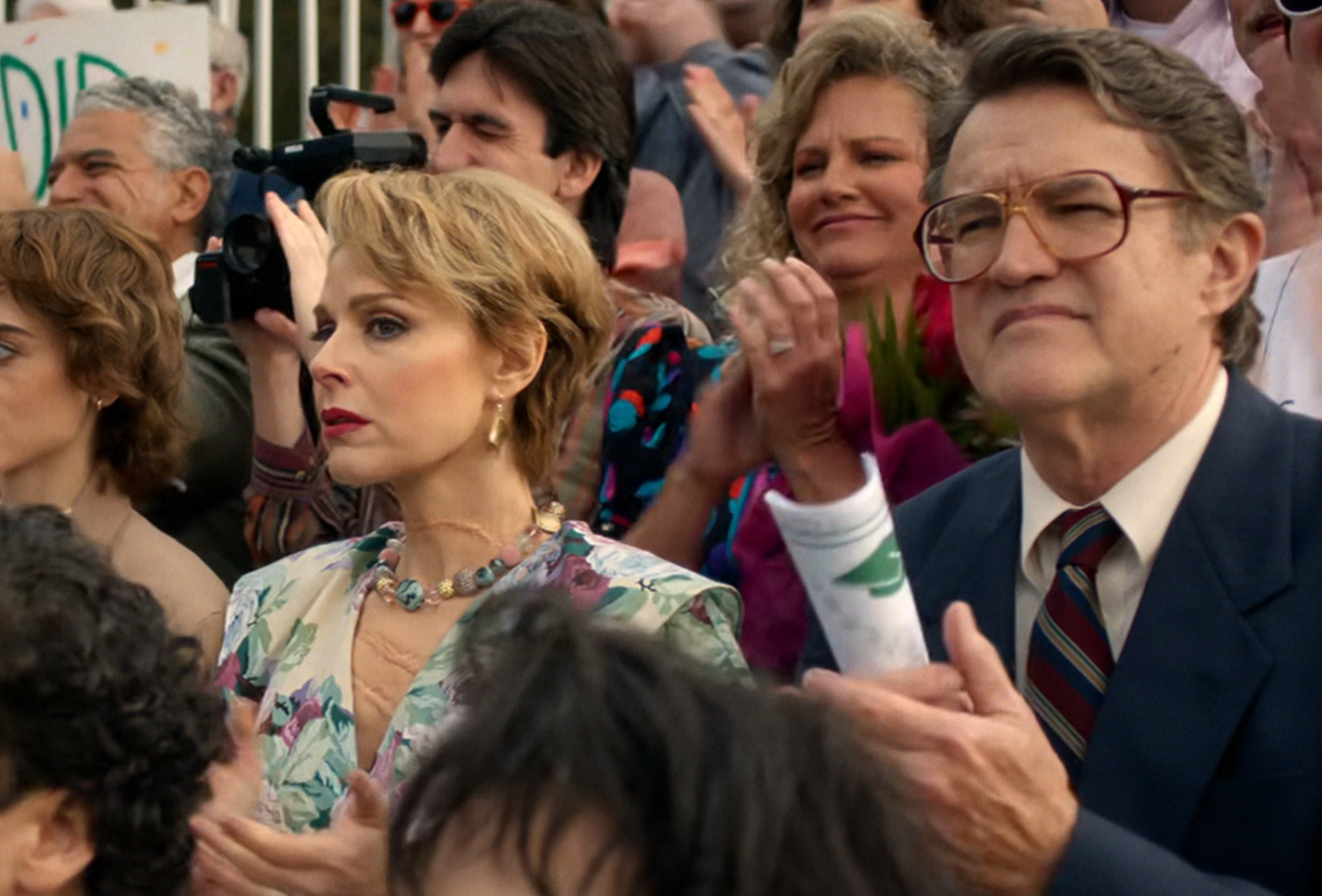  a woman in a floral blazer and a man with glasses in a suit and tie