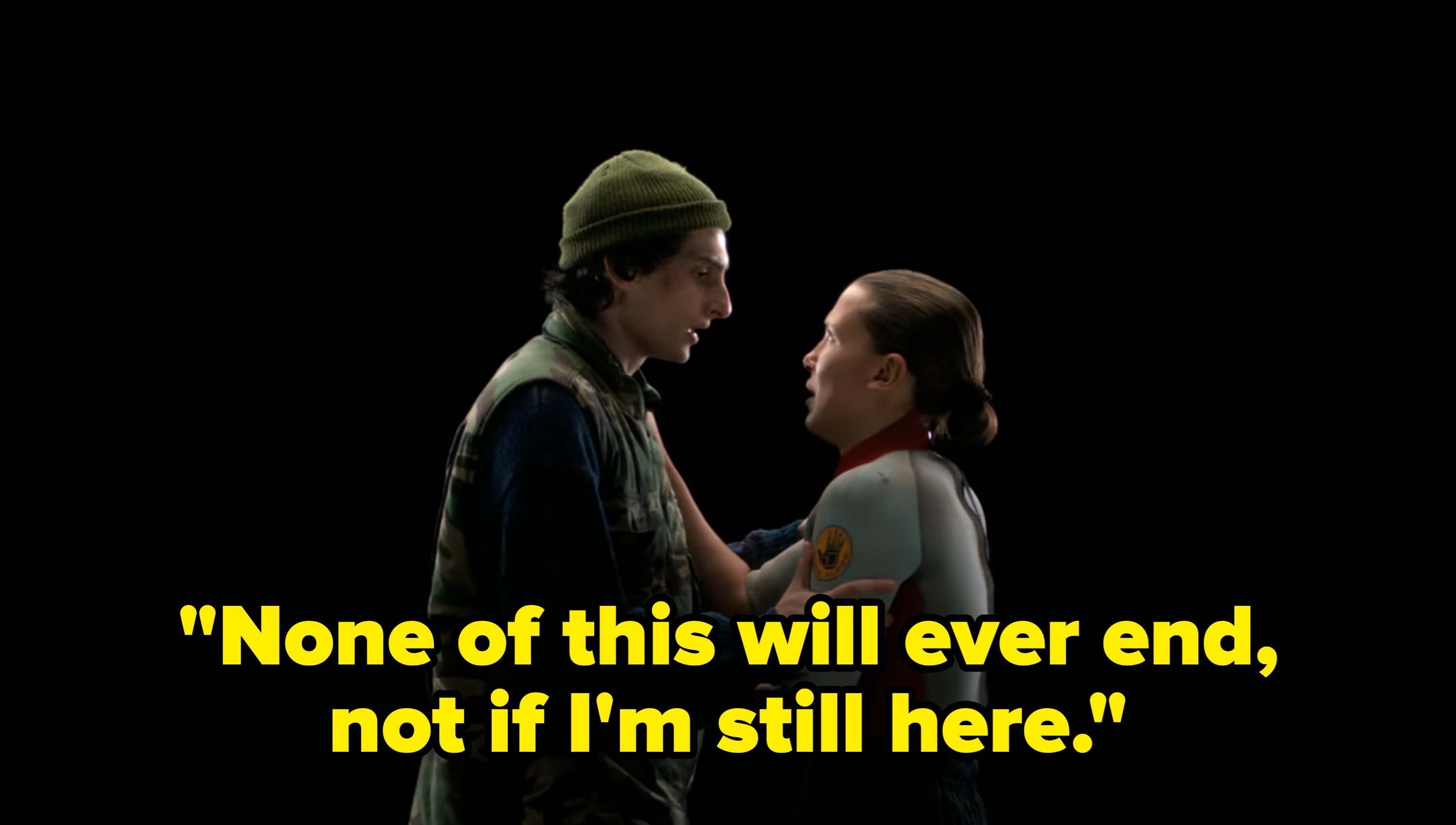  one in a camo vest, beanie, and the other with slicked-back hair, wearing a wetsuit. Dark background