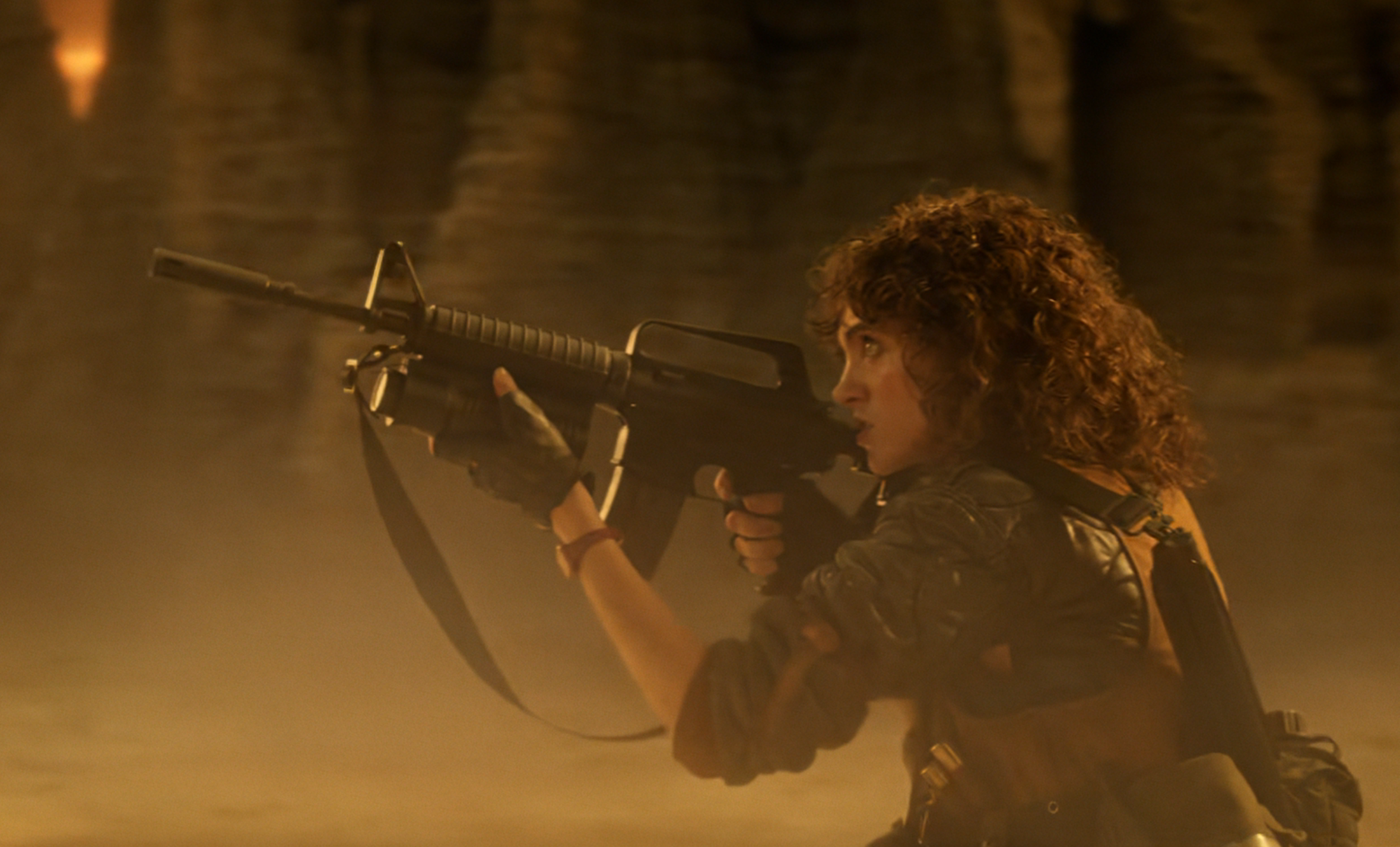 Person crouching with a rifle in an action-packed scene, set in a dimly lit cave environment