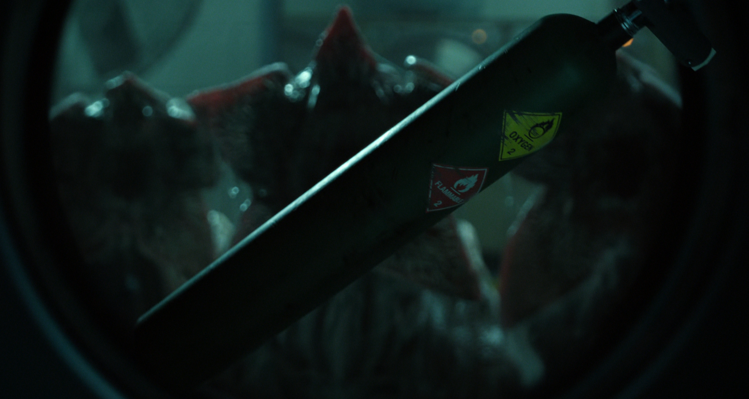 A creature with an open mouth and sharp teeth is partially visible through a circular window, creating a tense and suspenseful scene