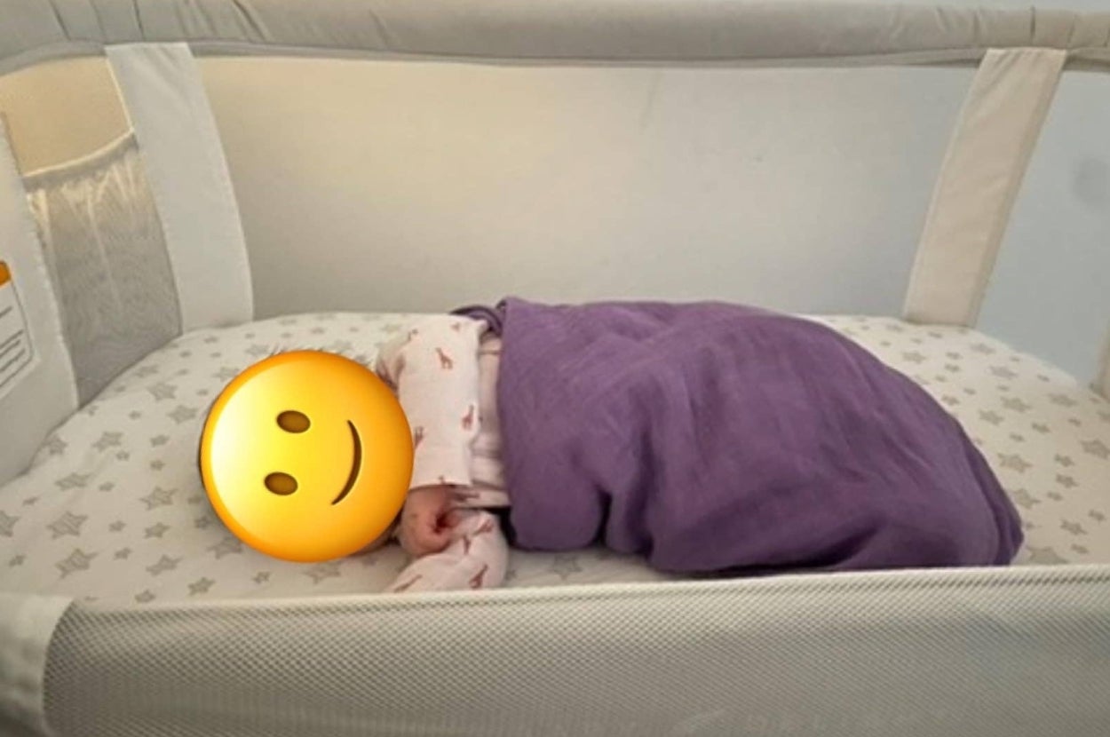 Baby sleeping in a crib, wrapped in a blanket. The mattress has a star pattern