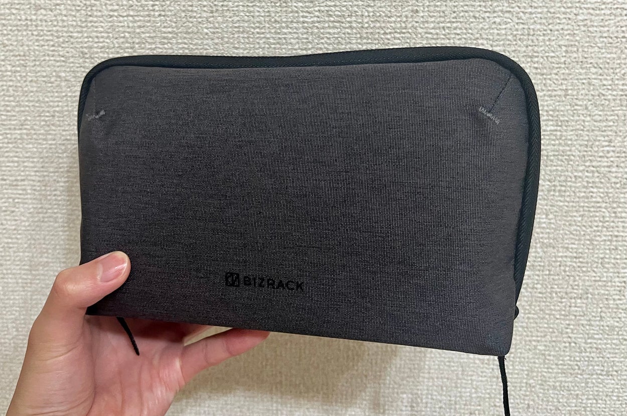 手に持たれた長方形のポーチ。シンプルなデザインで、BIZRACKのロゴが見える。