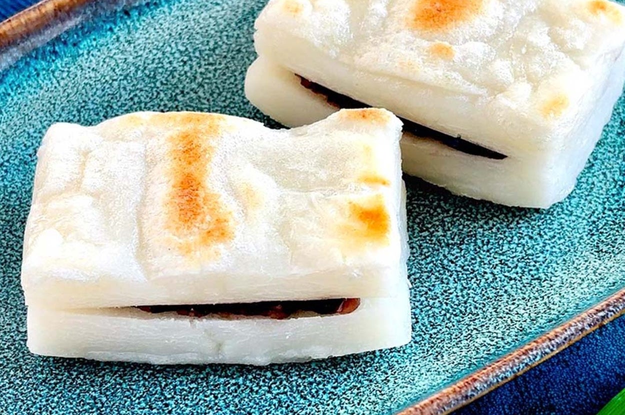 焼き餅にあんこが挟まれた二つの和菓子が青いプレートに載っている。