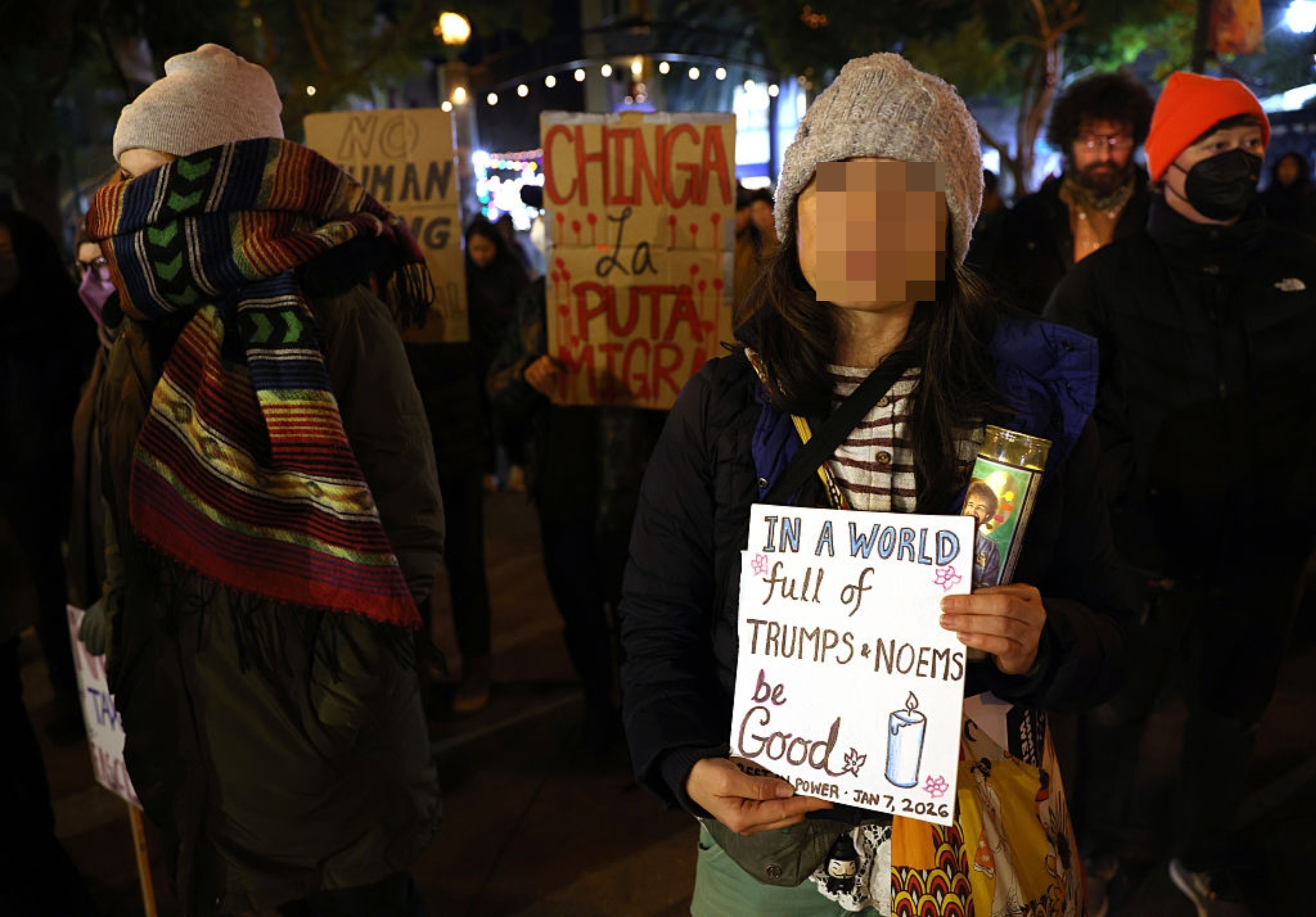 En person som har på seg en lue holder et protestskilt med teksten 