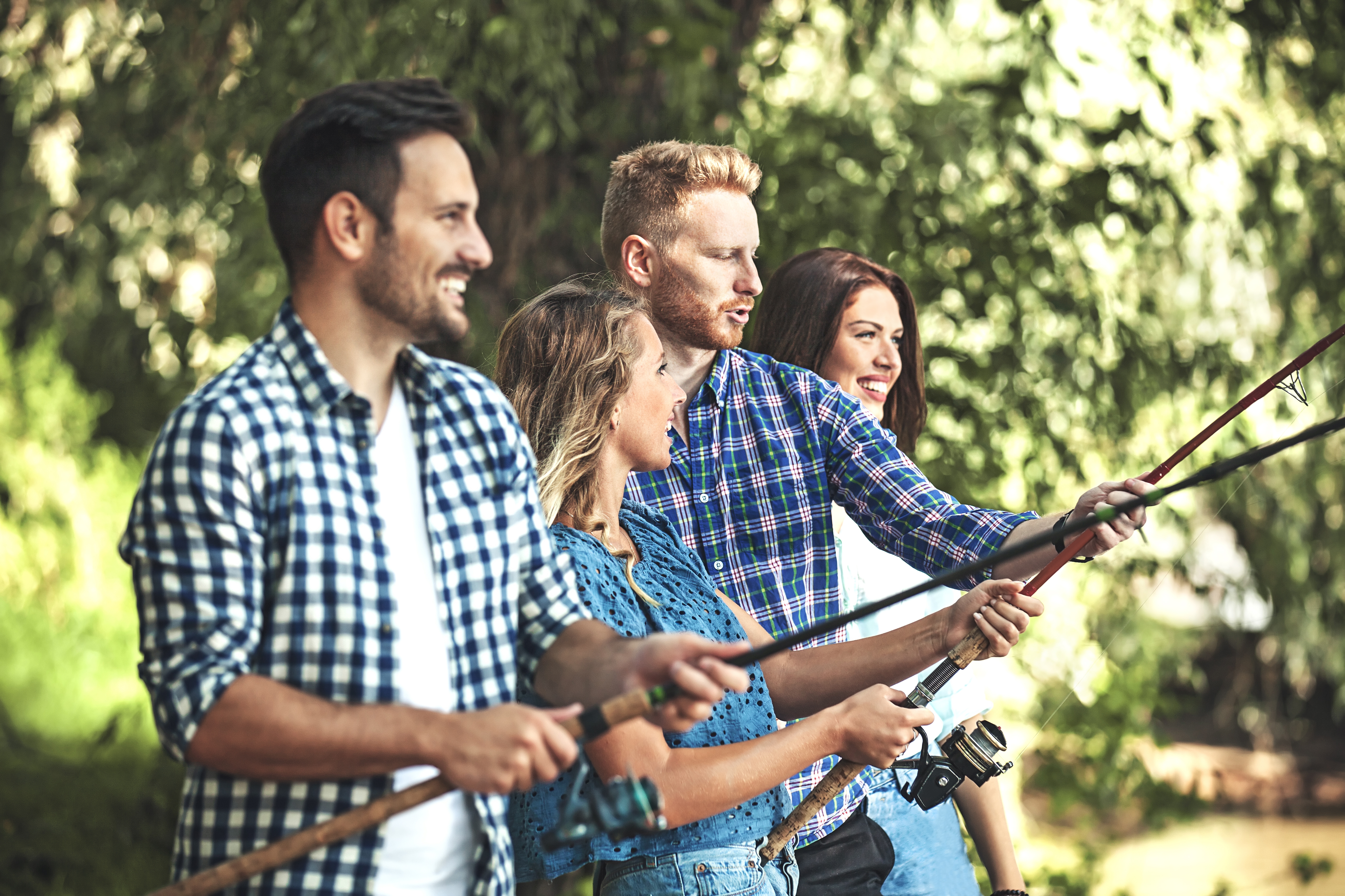 Four radical   sportfishing  outdoors, smiling and enjoying the activity. They are casually dressed and focused connected  the h2o  ahead