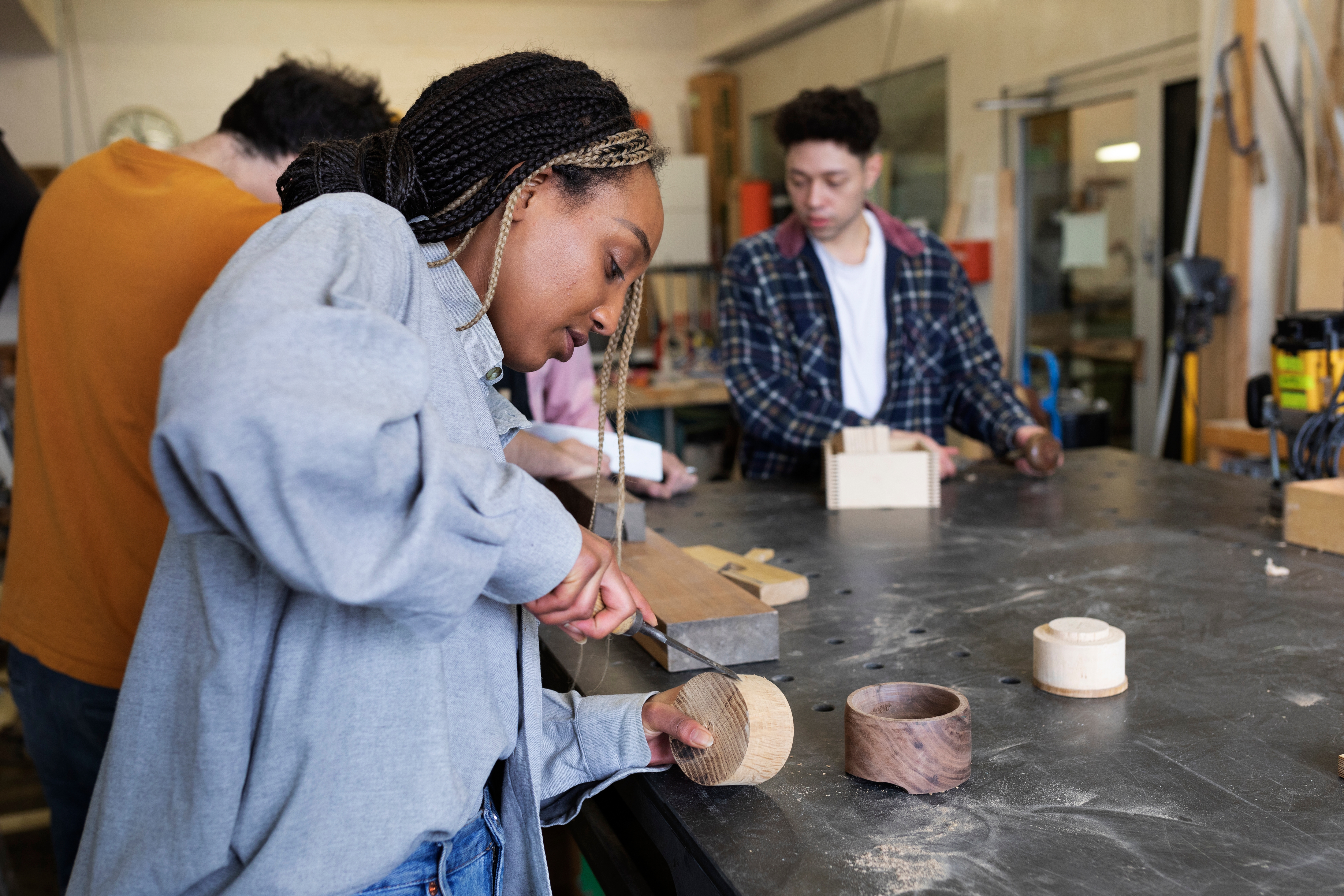 People engaged successful  woodworking successful  a workshop, focusing connected  projects astatine  a ample  table