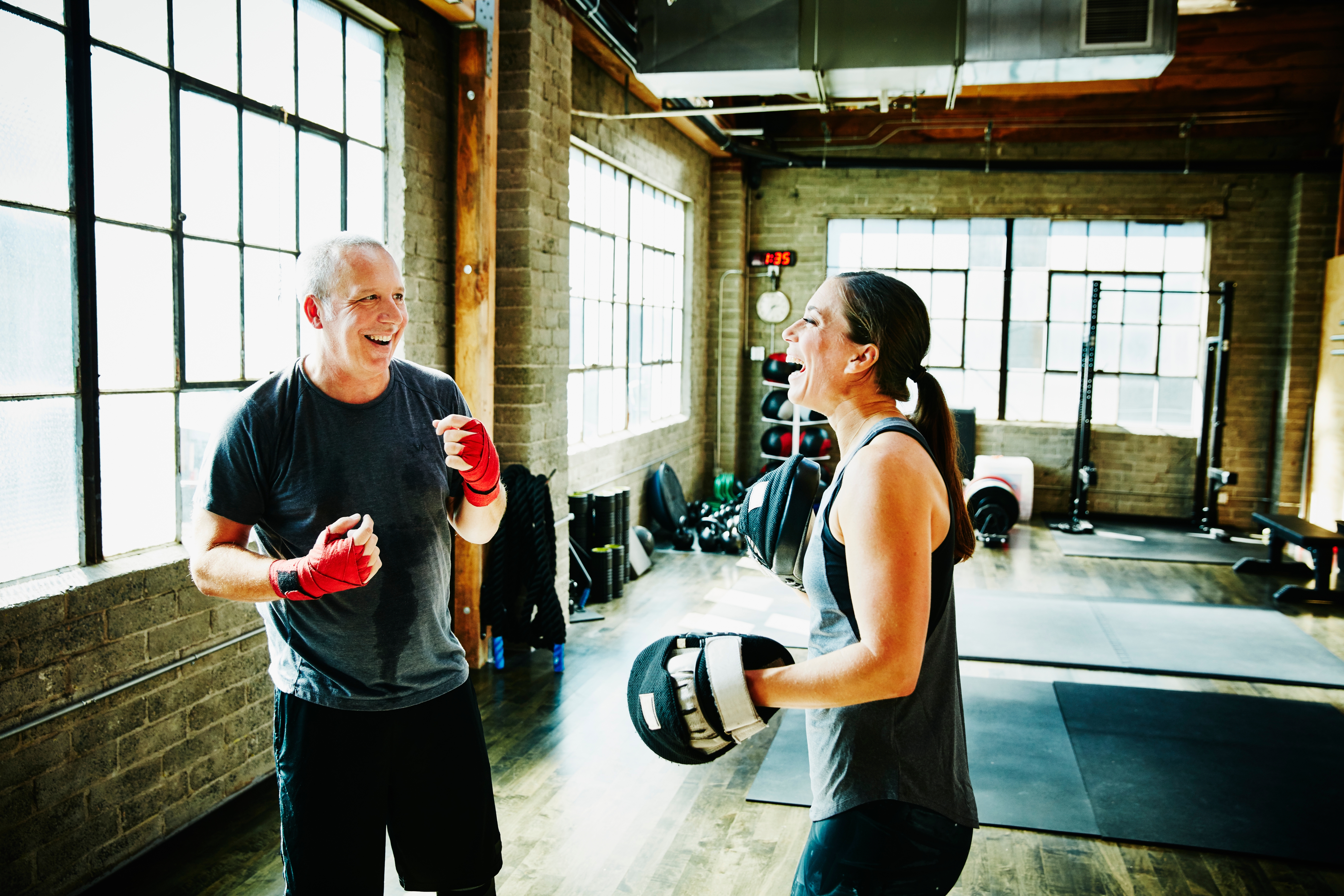 Two radical   successful  a gym laughing and boxing with gloves on, sharing a lighthearted workout moment
