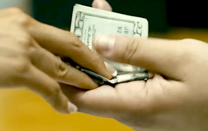 Hands exchanging a small stack of money, signaling a transaction