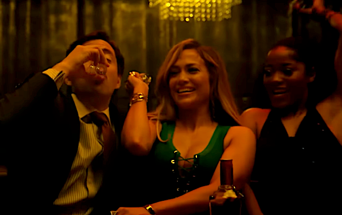 Three people at a bar: one drinks from a glass, another smiles in a green dress, and the third raises their arm in celebration. The setting is lively