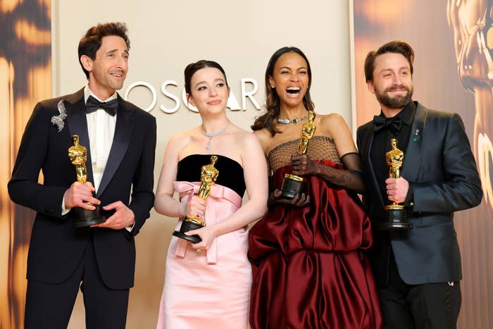 Empat orang berpose dengan Oscar, mengenakan pakaian formal di sebuah acara penghargaan