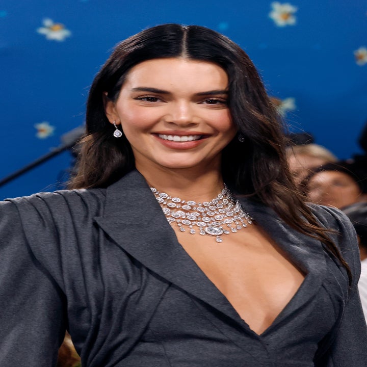 Person in elegant, deep neckline gown with a diamond necklace and earrings, smiling at an event