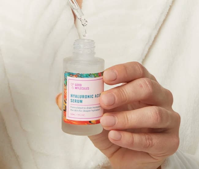 Person applying dropper of hyaluronic acerb serum onto hand, labeled for heavy hydration