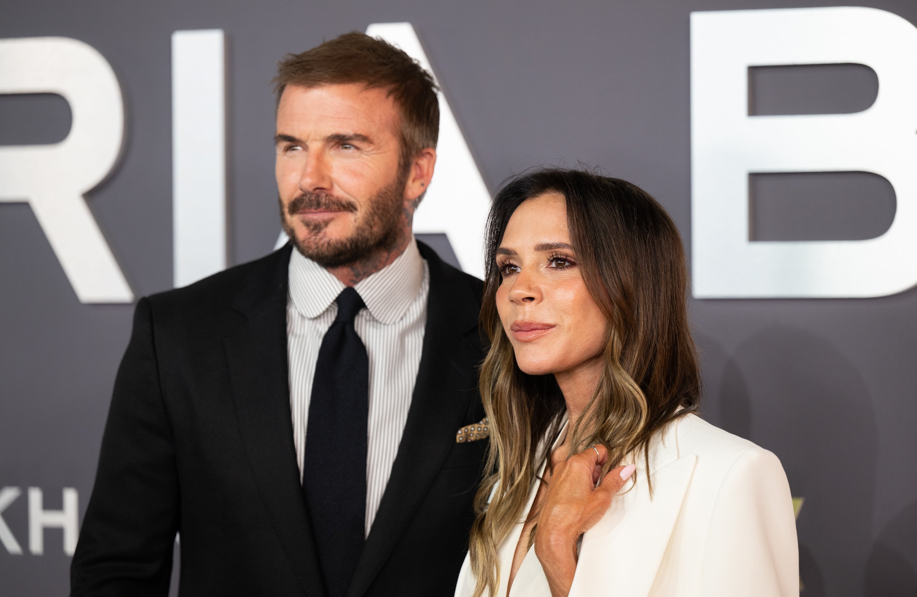 David dan Victoria Beckham berpose di karpet merah; laki-laki memakai jas dan dasi, dan perempuan memakai blazer putih dengan atasan berpotongan rendah