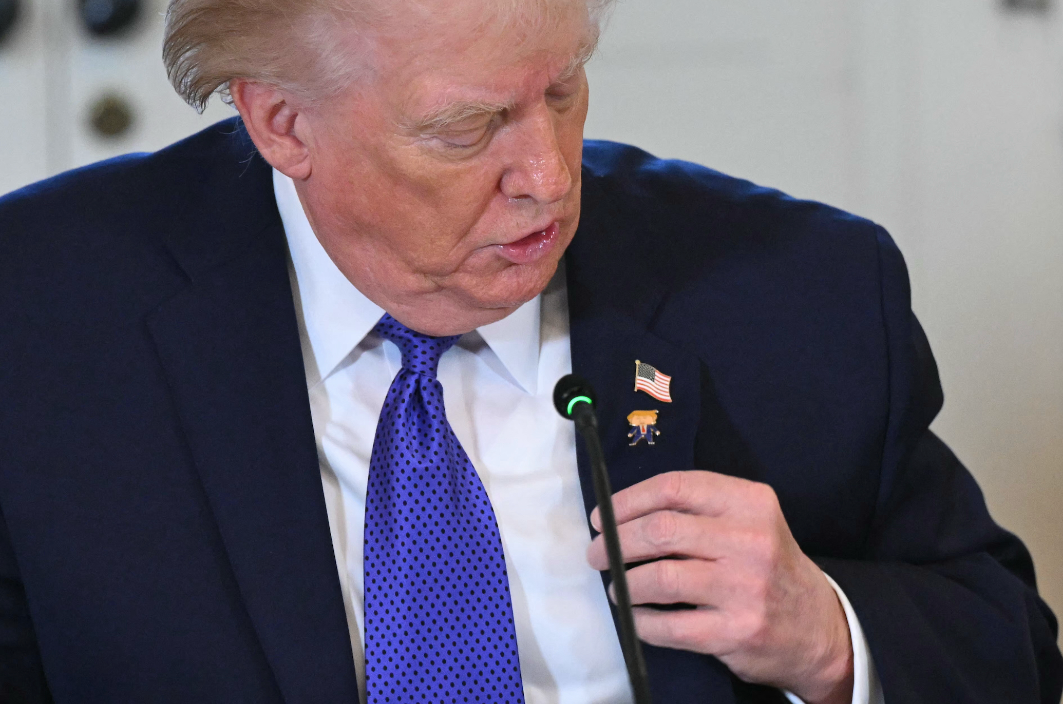 Person i dress og slips justerer amerikansk flaggnål på jakkeslaget, og virker fokusert og oppmerksom