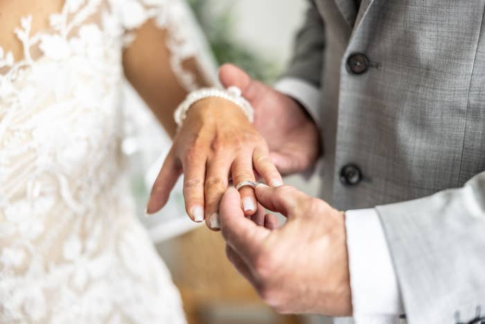 A mates  exchanges rings astatine  a wedding ceremony. The bride wears a lace dress, and the groom is successful  a suit