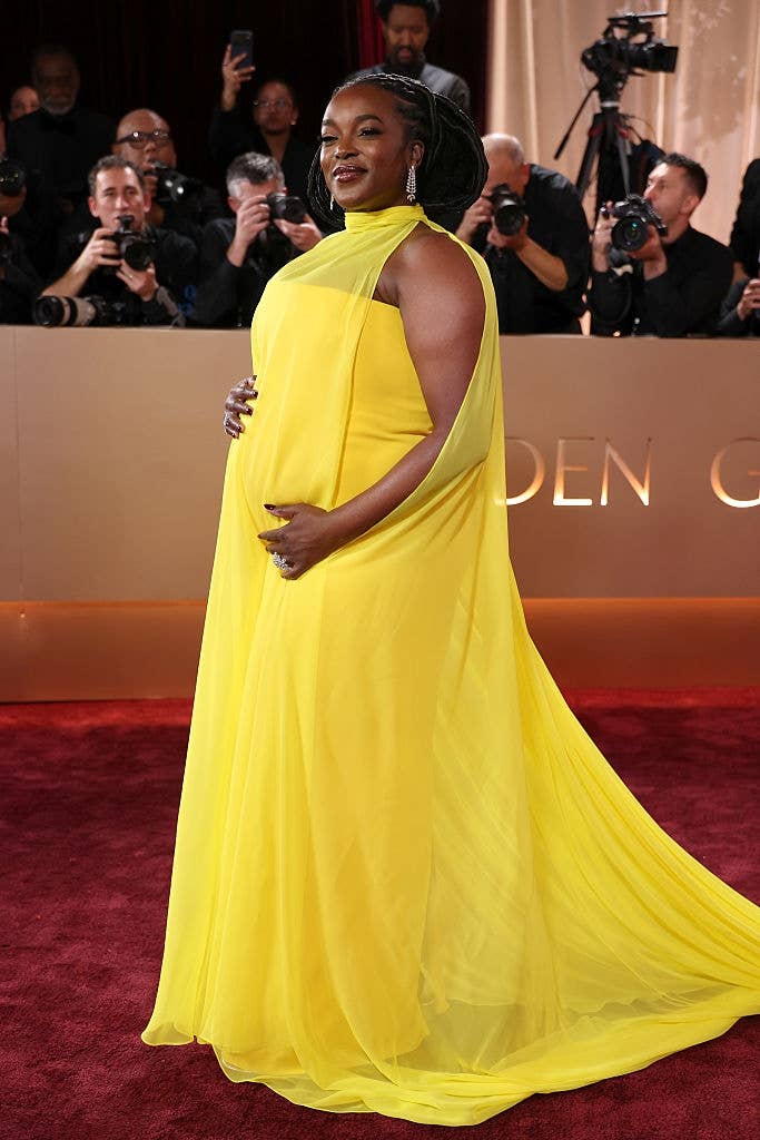 Person successful  elegant gown cradles babe  bump connected  reddish  carpet, photographers successful  background